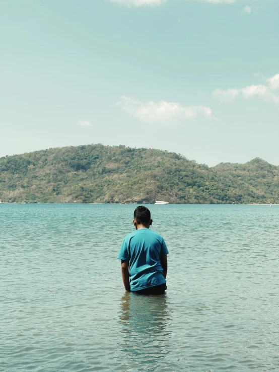 a man is sitting in the water by the hill