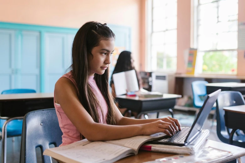 the girl is doing homework on her laptop