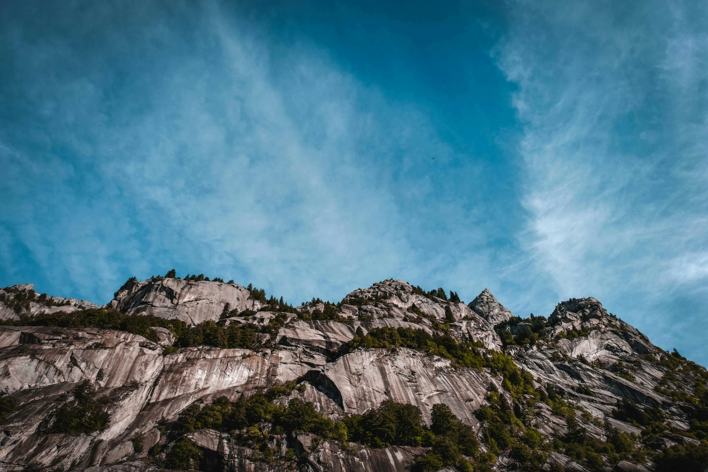 some rocky cliff and trees under a blue sky