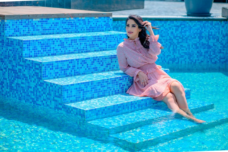 a woman sits on the steps next to a pool