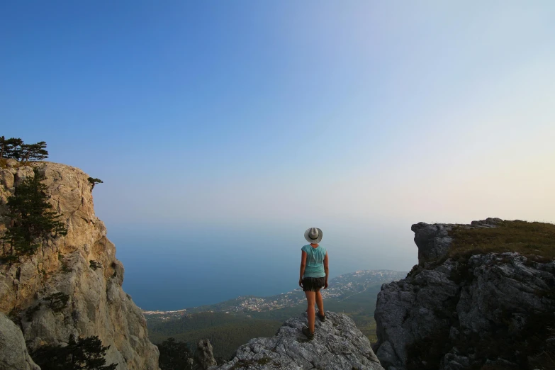 woman standing on top of a large rock formation overlooking a valley