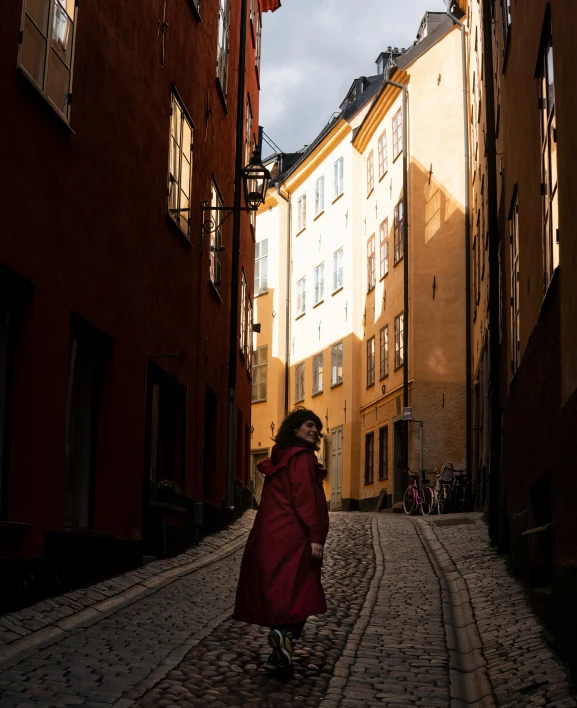 a woman in a red robe is standing on a cobblestone street