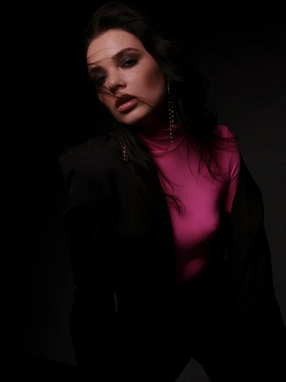 woman in dark with pink top and jacket looking away