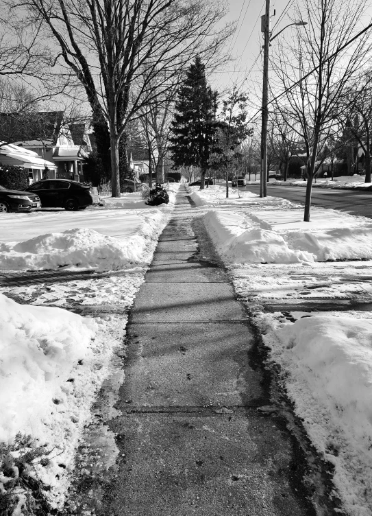 a snowy sidewalk on the side of the street with no cars in the snow