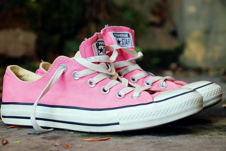 pink shoes with laced laces and laces sit on concrete