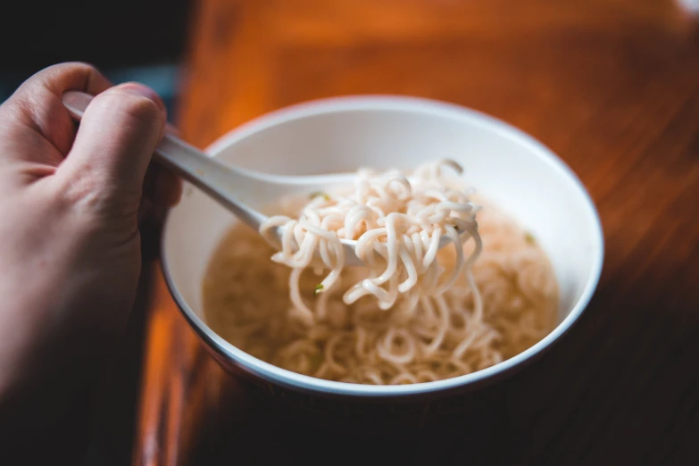 a bowl filled with noodles and sauce being held up