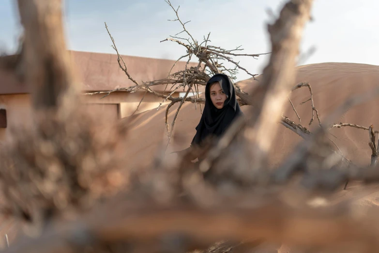 a young woman standing next to a dry tree