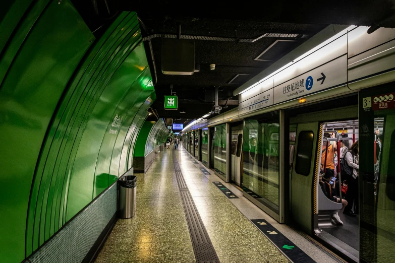 an empty subway station next to an exit and a green sign