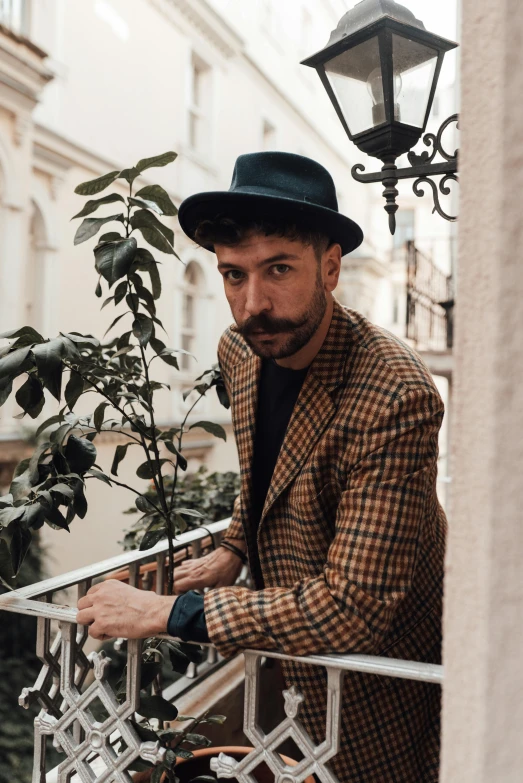 a man standing near a tree in a coat and hat