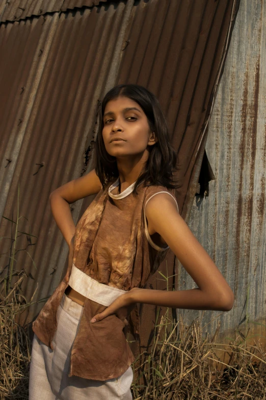 a girl standing in a field by an old building