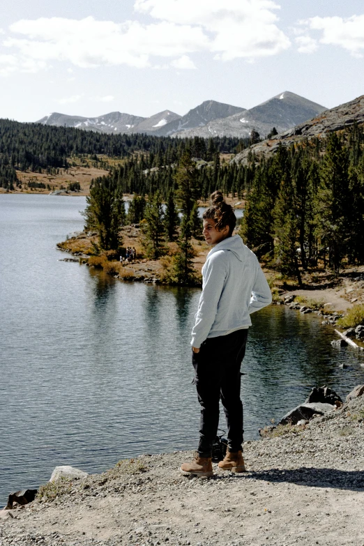 a woman stands on the shore of a lake looking at the sky