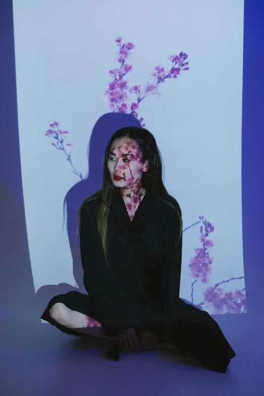 woman with flowers painted on face sitting in a purple room