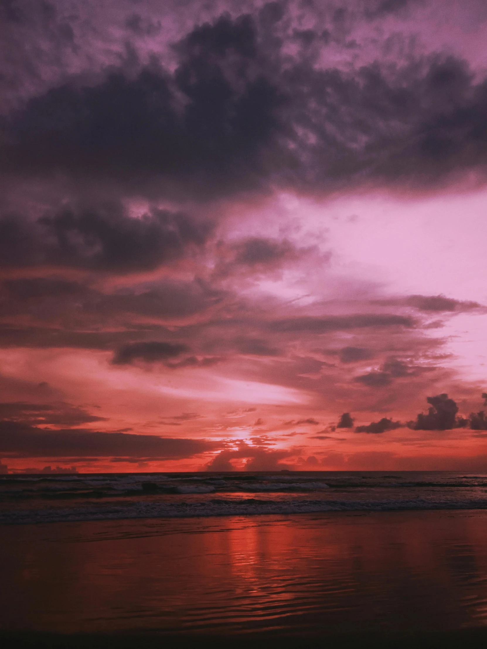 an orange sunset behind the clouds over a beach