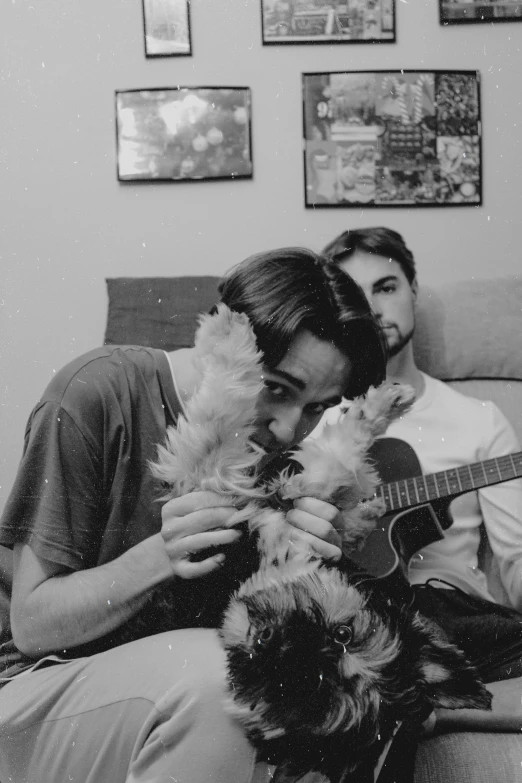 two men are playing a guitar and two dogs