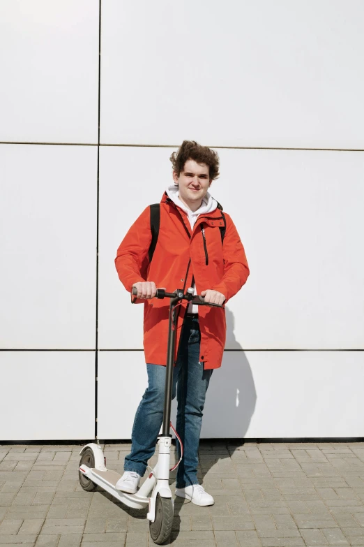 man on electric scooter standing next to wall