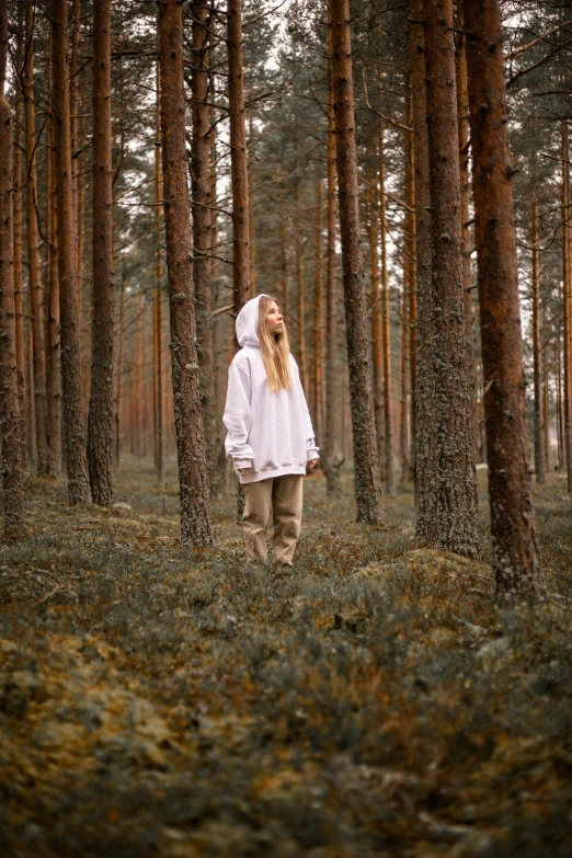 a person standing in the woods alone, wearing a hooded jacket