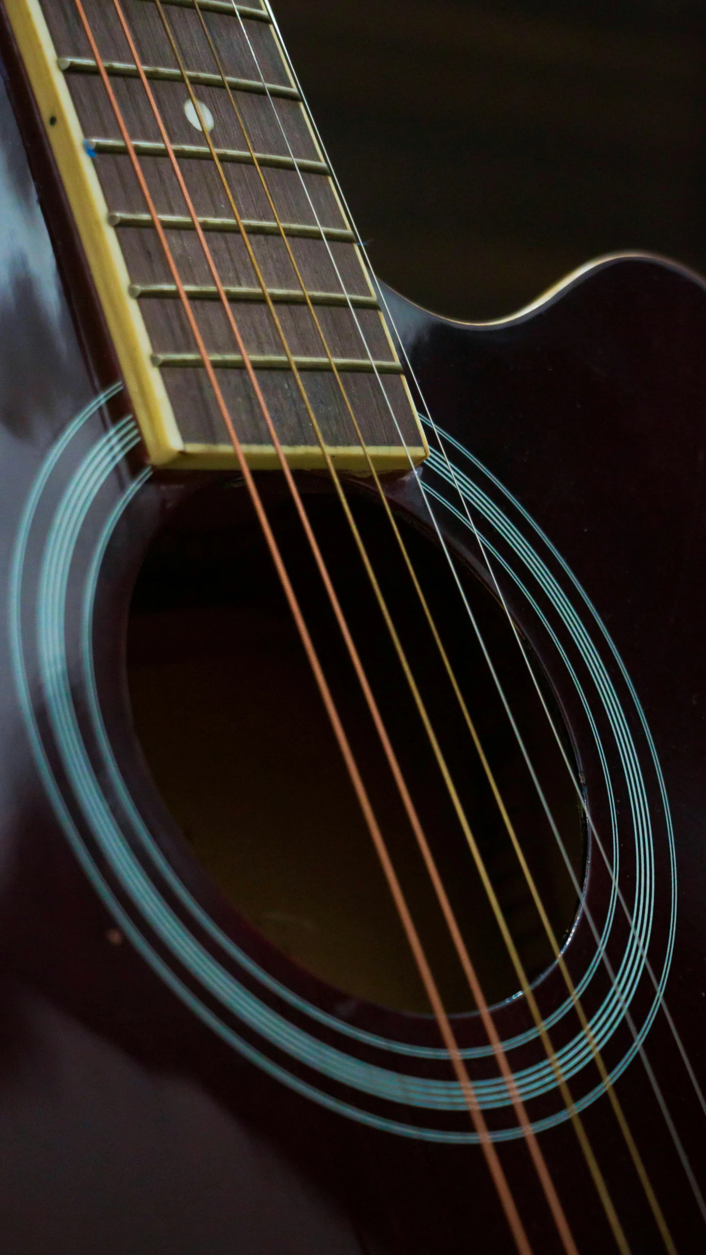 an acoustic guitar is propped against a black background