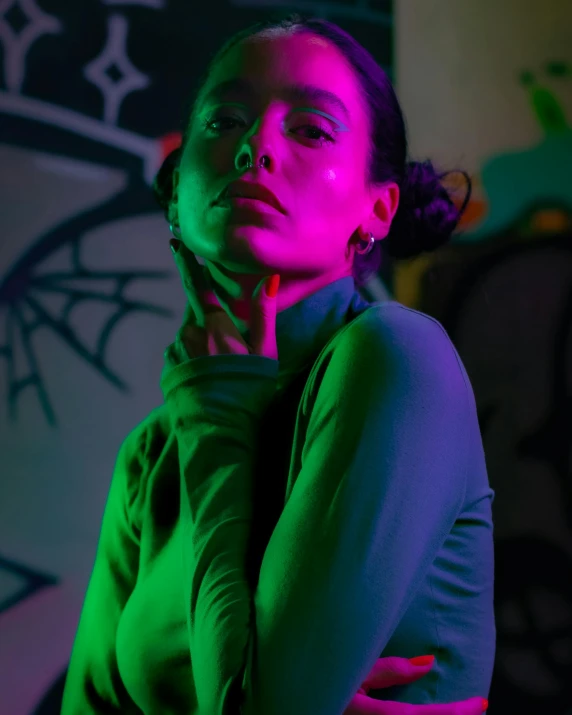 young black woman with neon light from the camera posing in front of colorful wall