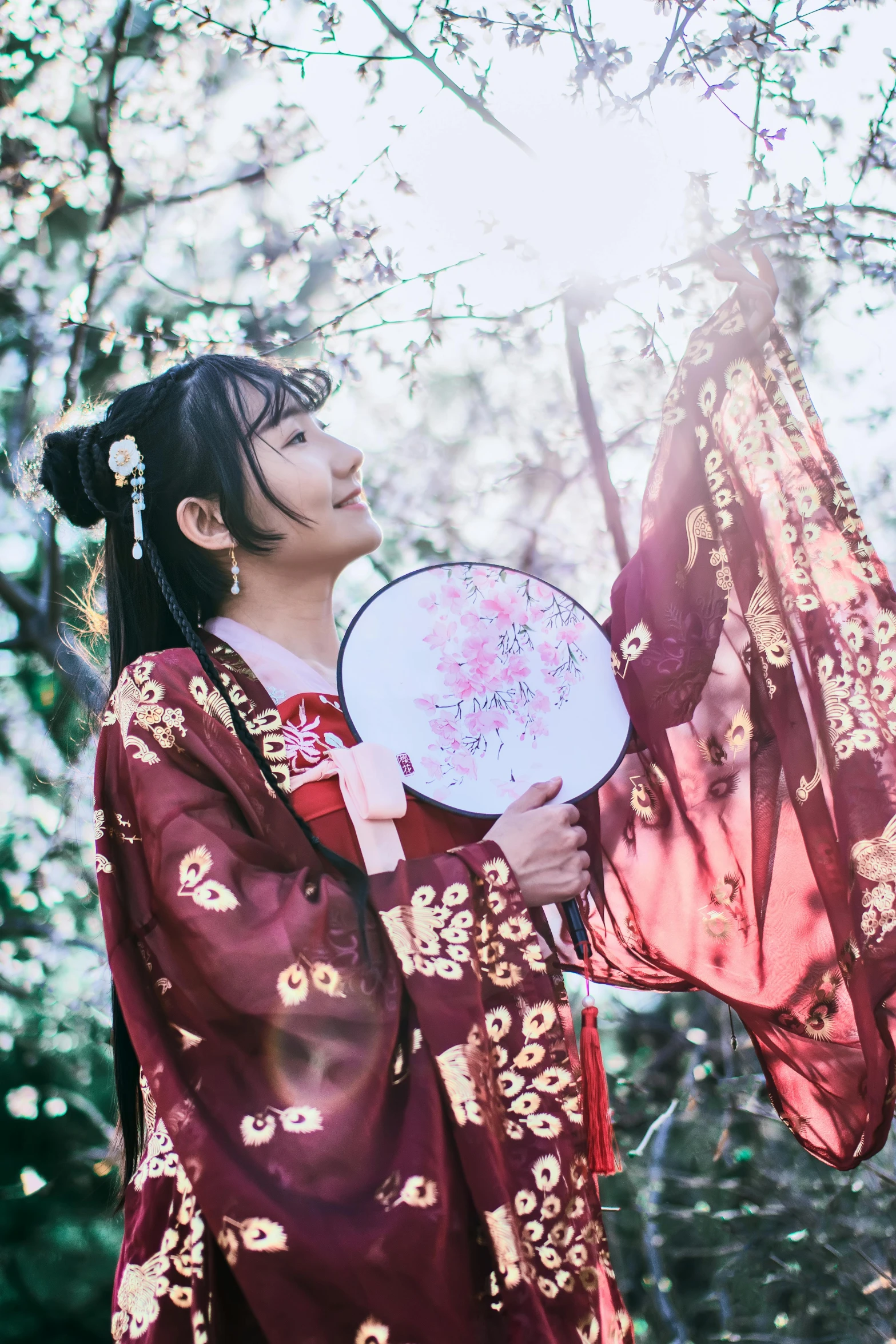 a woman wearing traditional clothing holds up an object in a tree