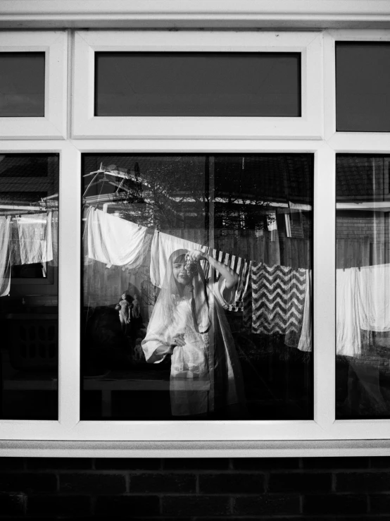 window reflection with white sheers with a lady waving