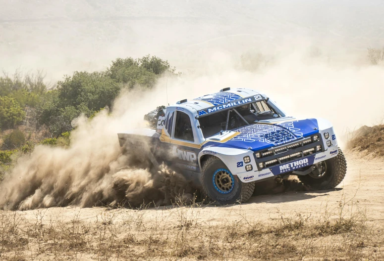 a blue truck drives through the dirt