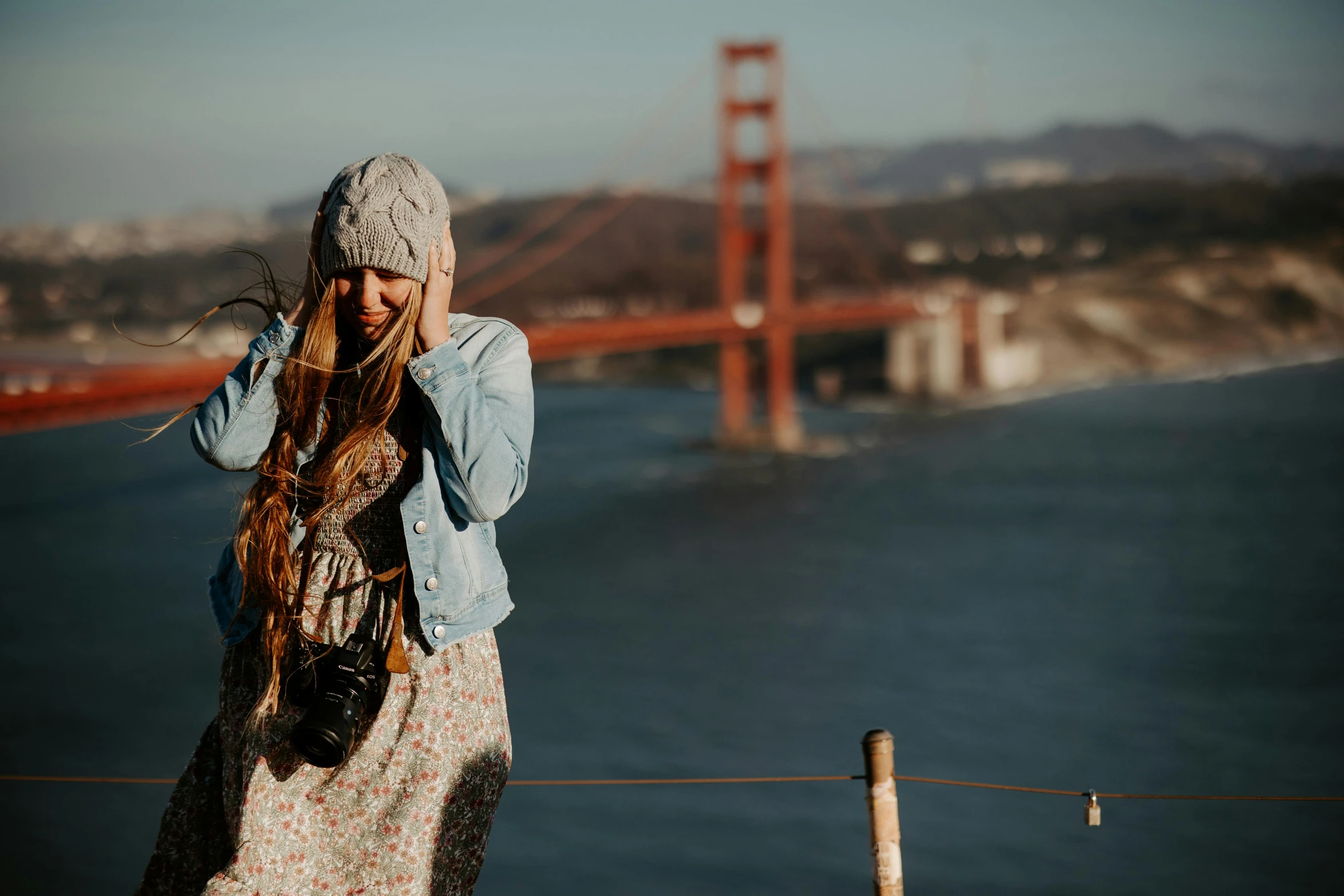 a woman standing by a bridge on a cell phone