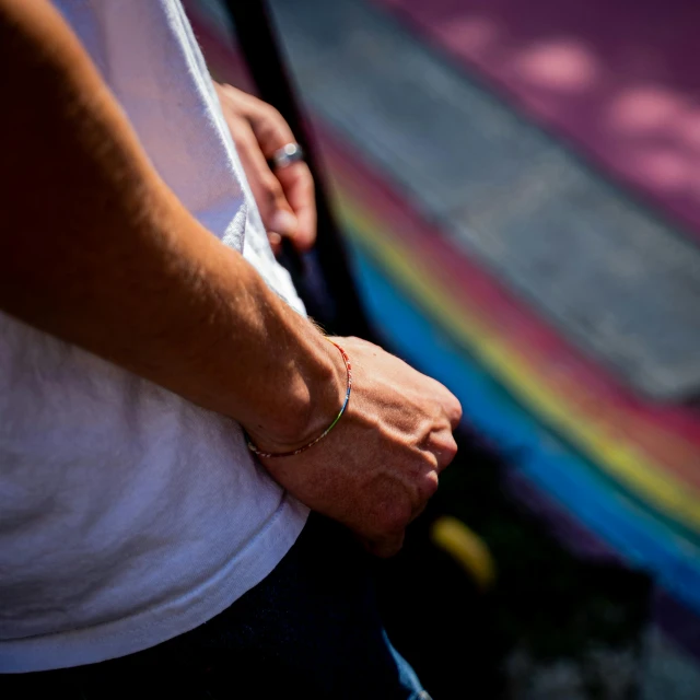 a person with a rainbow celet standing on a sidewalk