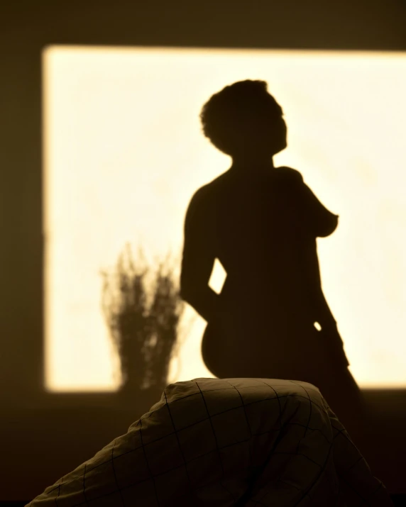 a girl is sitting against a wall in the sun