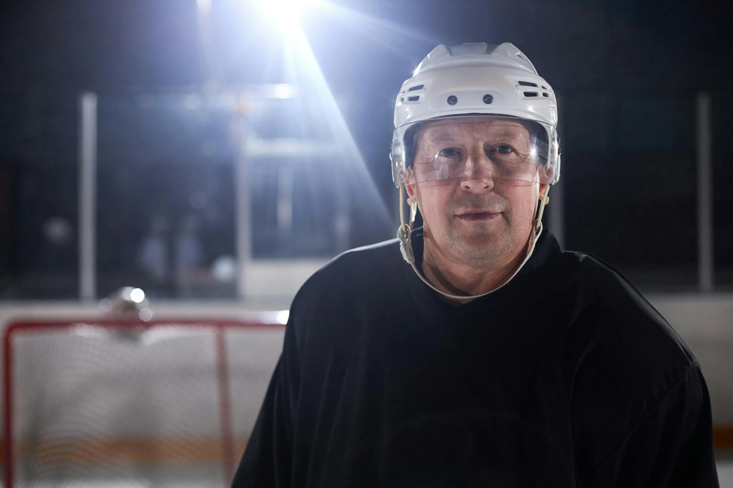 a man wearing a white hockey helmet and wearing a black shirt