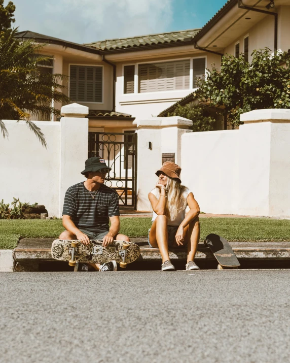 two people are sitting on a curb together with skateboards