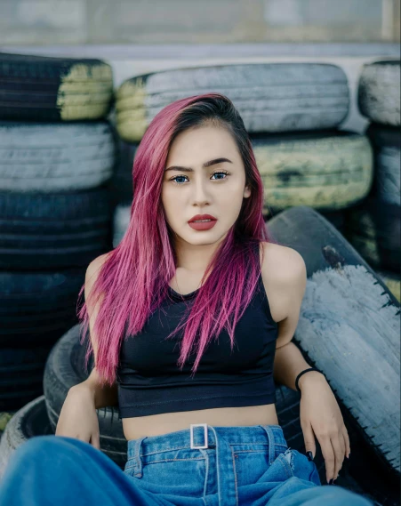 a woman sitting on top of some tires with pink hair