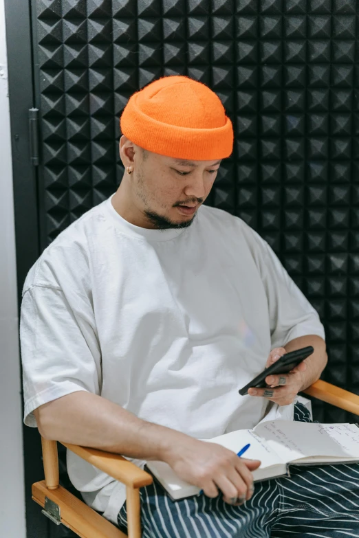 a man in orange hat is writing on a book