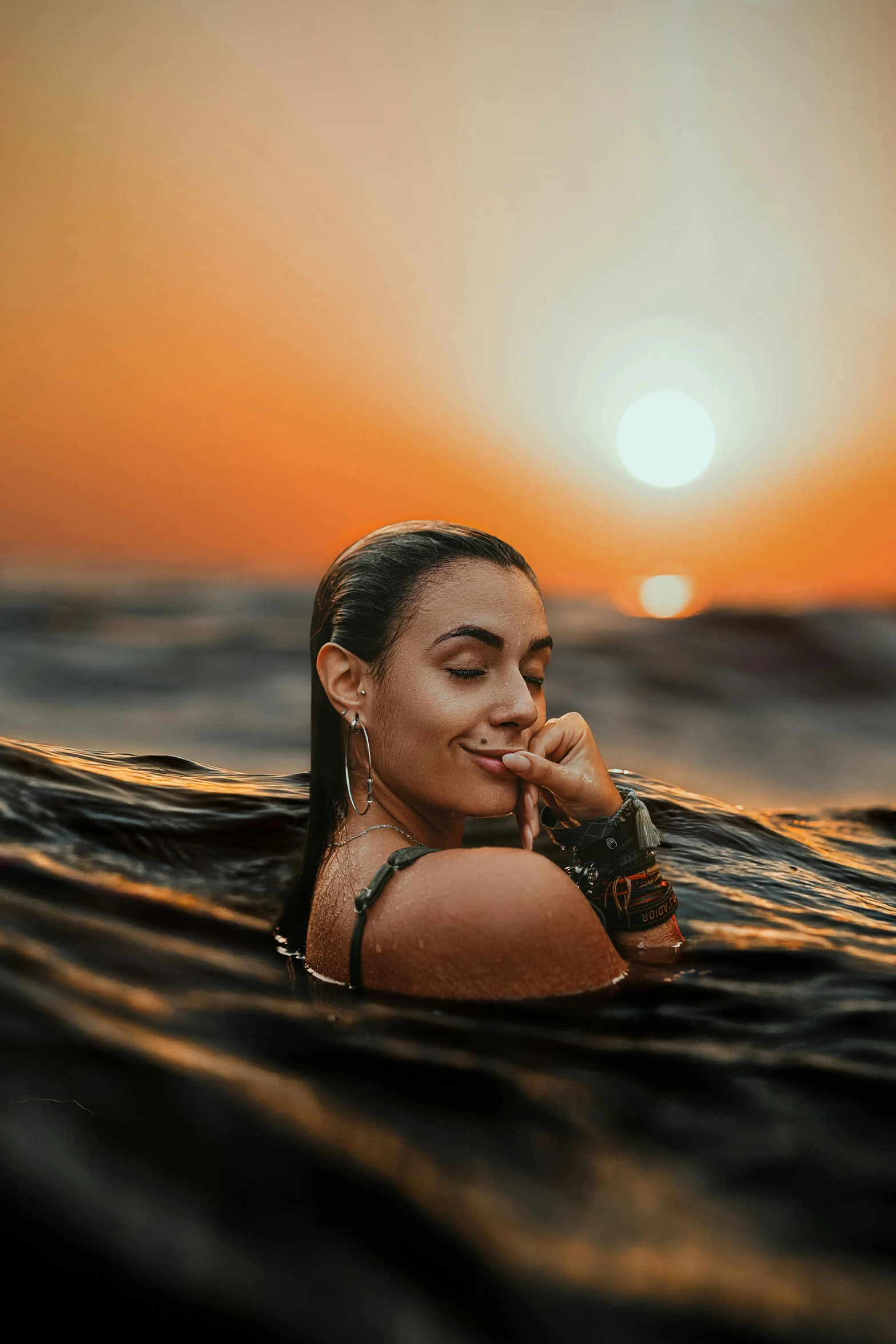 woman in bikini swimming near a sunset