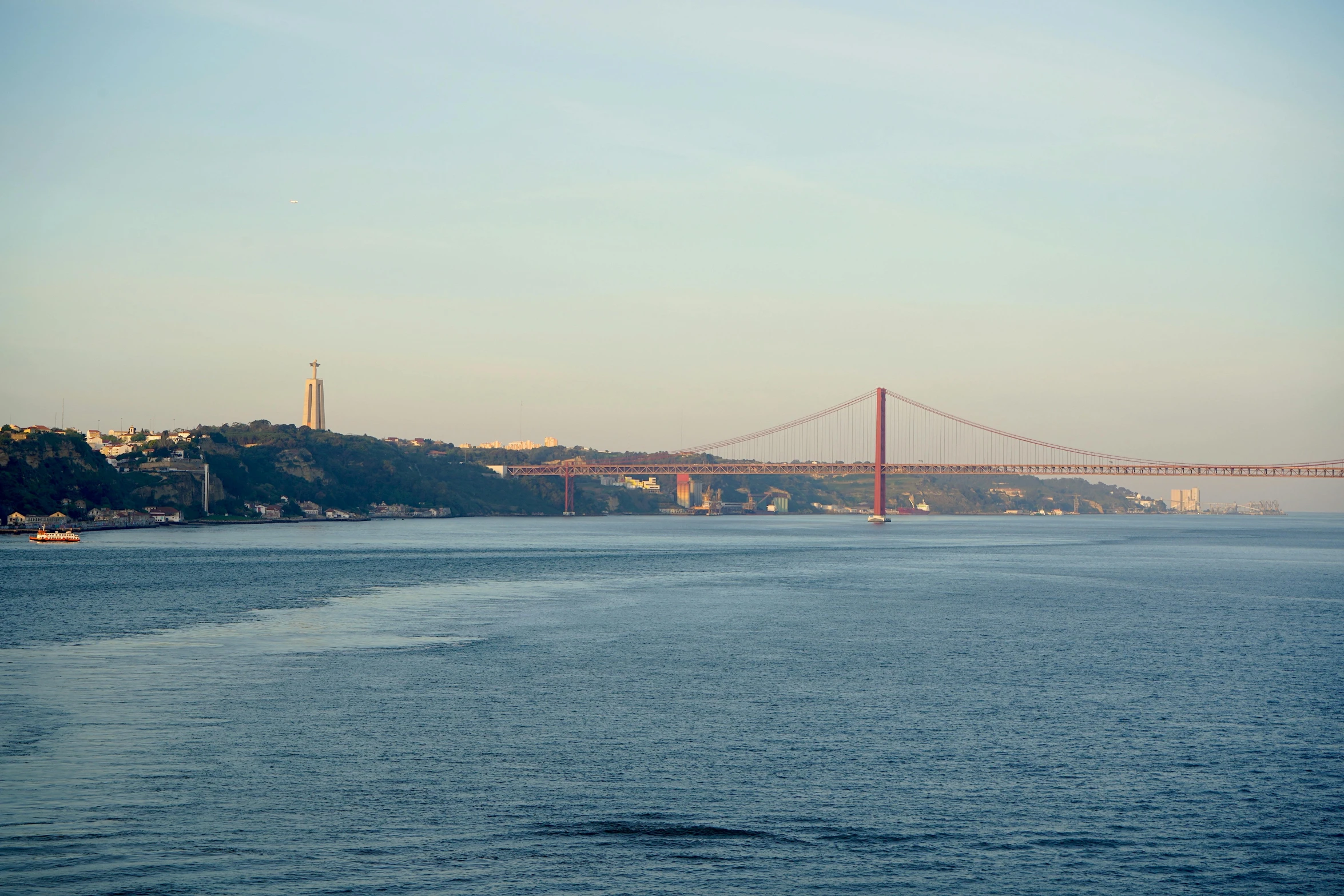 the water is calm and blue but a view of an over pass bridge