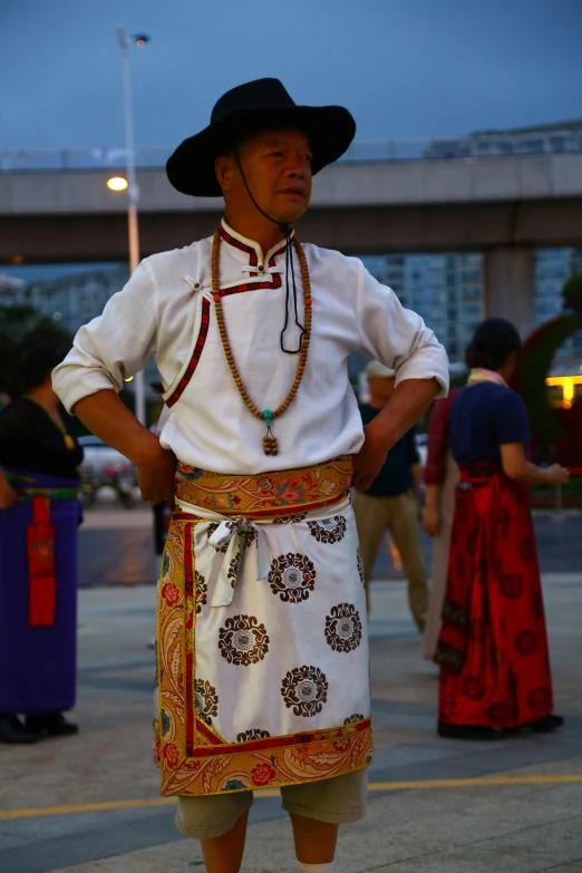 a man in a traditional costume, wearing a hat and a necklace