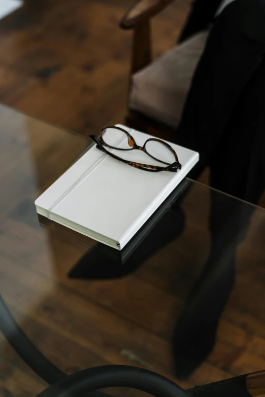 glasses on top of a notebook sitting on a desk