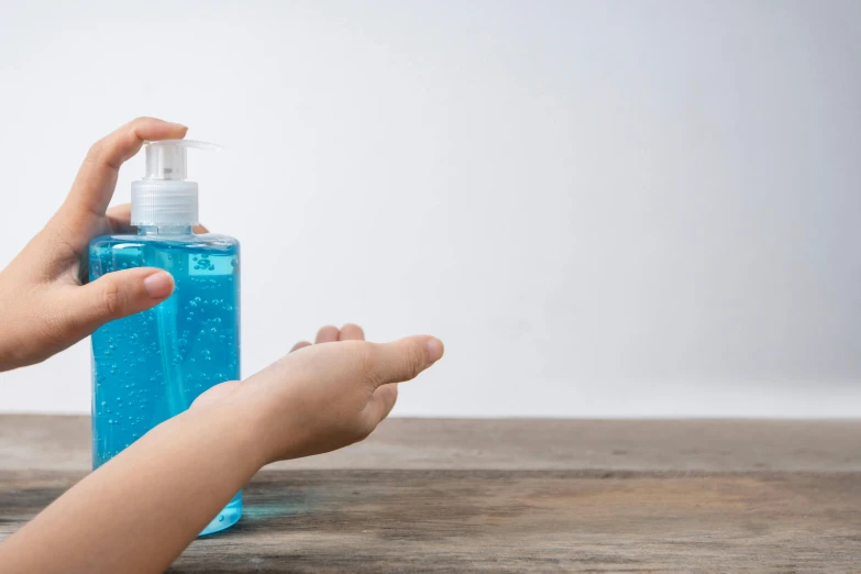 a person sitting at a table holding onto a hand sanitizer