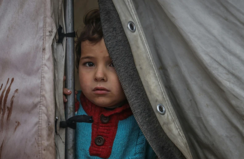 young child hiding from the cold weather in a tent