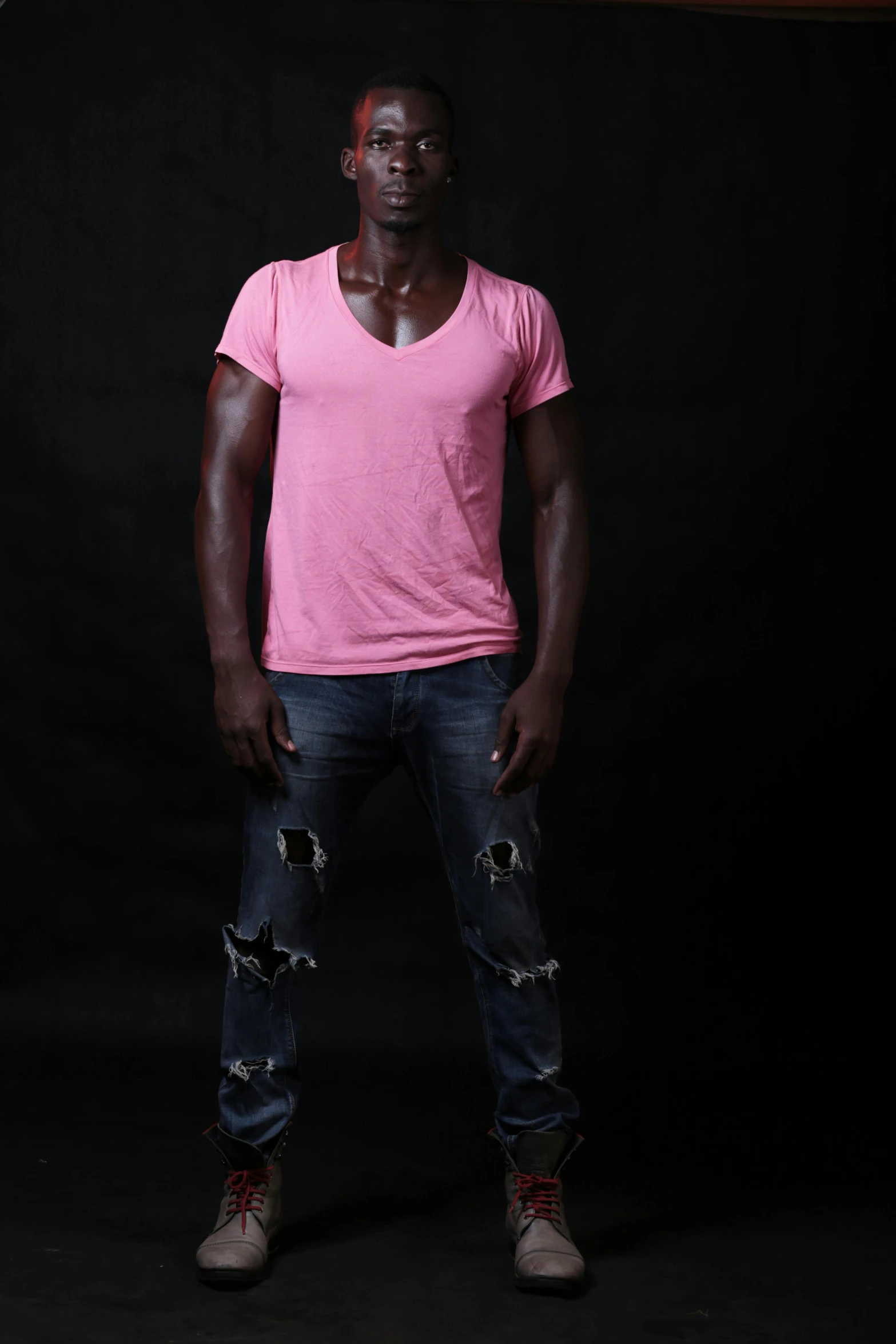 a man wearing ripped jeans and a pink t - shirt