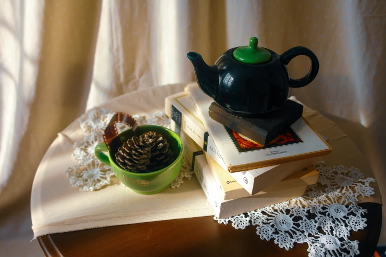 a pile of books sitting next to a teapot and a cup