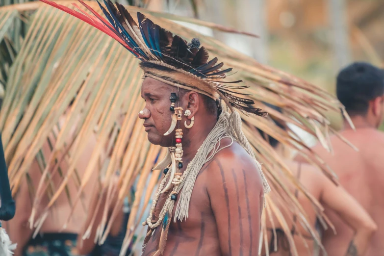 a person with tattoos on their chest wearing head dress