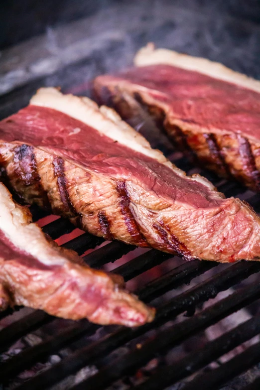 steaks are cooking on an outdoor grill