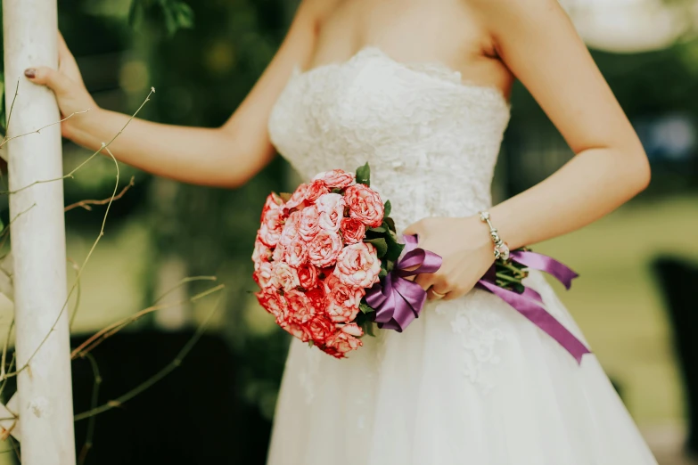 a woman wearing a white wedding dress holding a bouquet of flowers