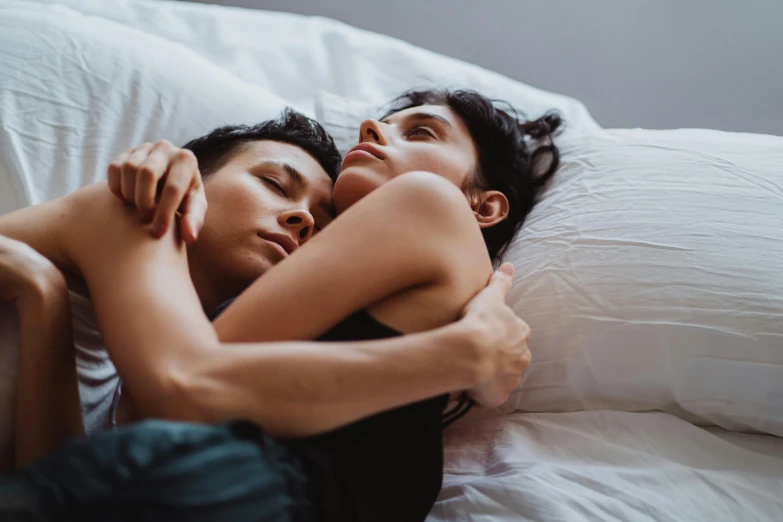 an asian and a white young man snuggled next to each other on their stomachs