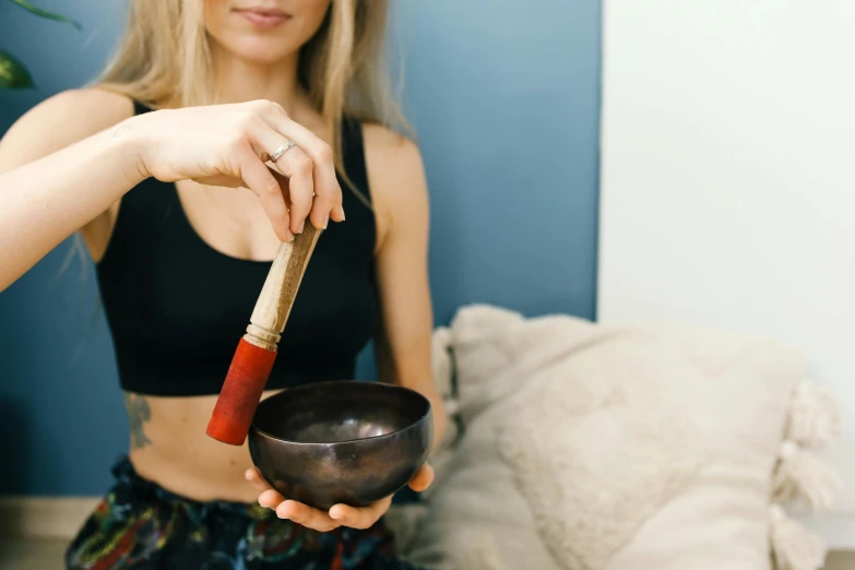 a woman holds a bowl and spoon in front of a couch