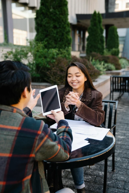 two asian people smile and hold their small tablet