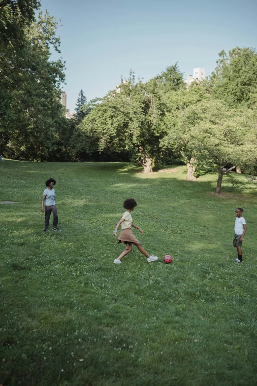 three children playing with a ball in the grass