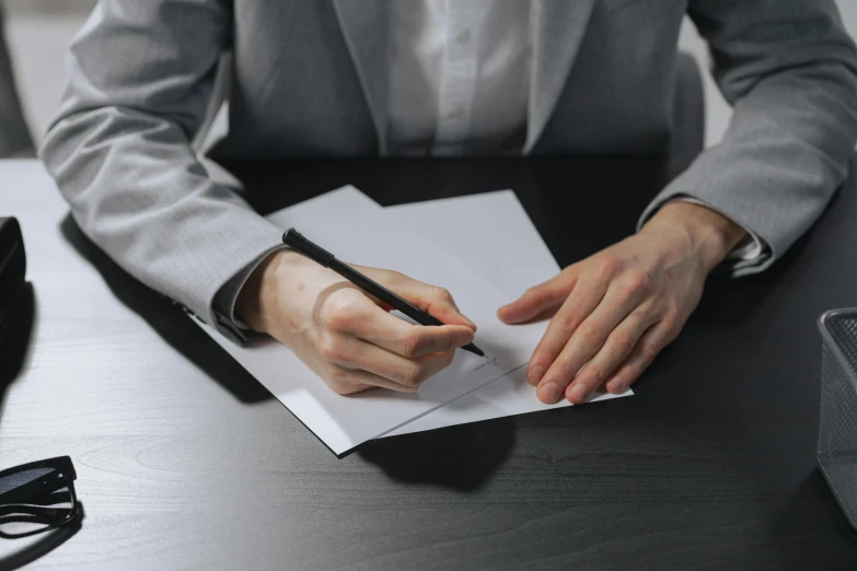 the person in a suit is holding onto a piece of paper and writing soing on it