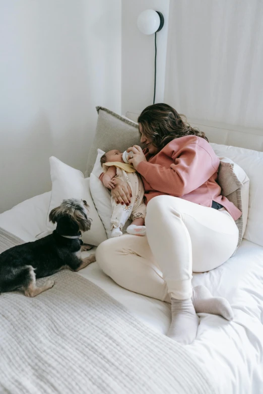 the woman is sitting on her bed with two dogs