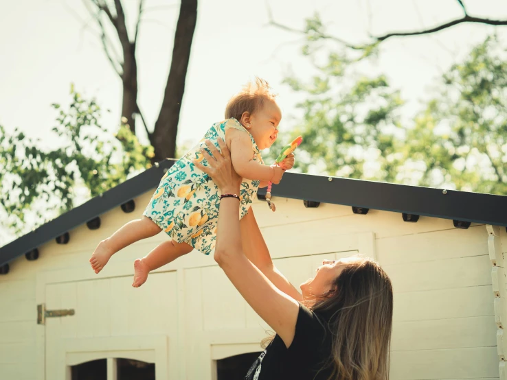 the woman is holding the little baby up outside